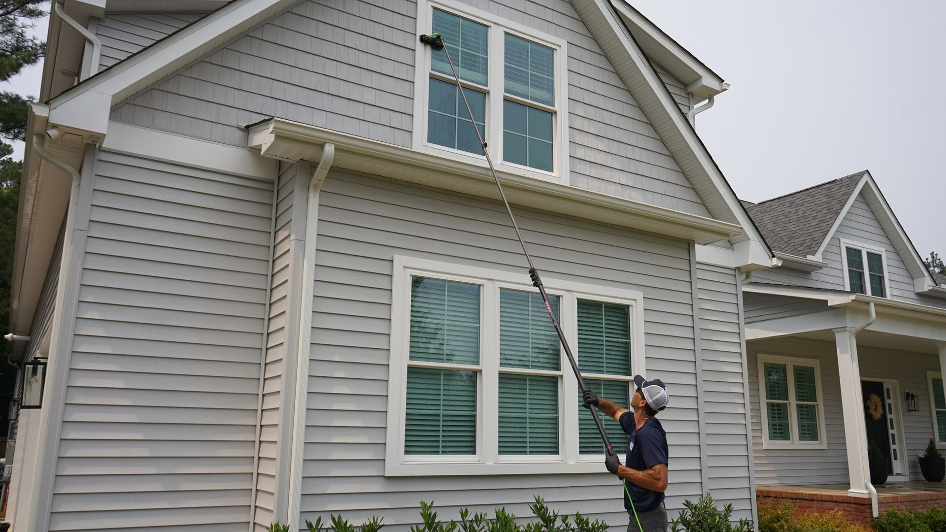 Coastal Shine technician cleaning second-story windows with a water-fed pole in Easton, MD.