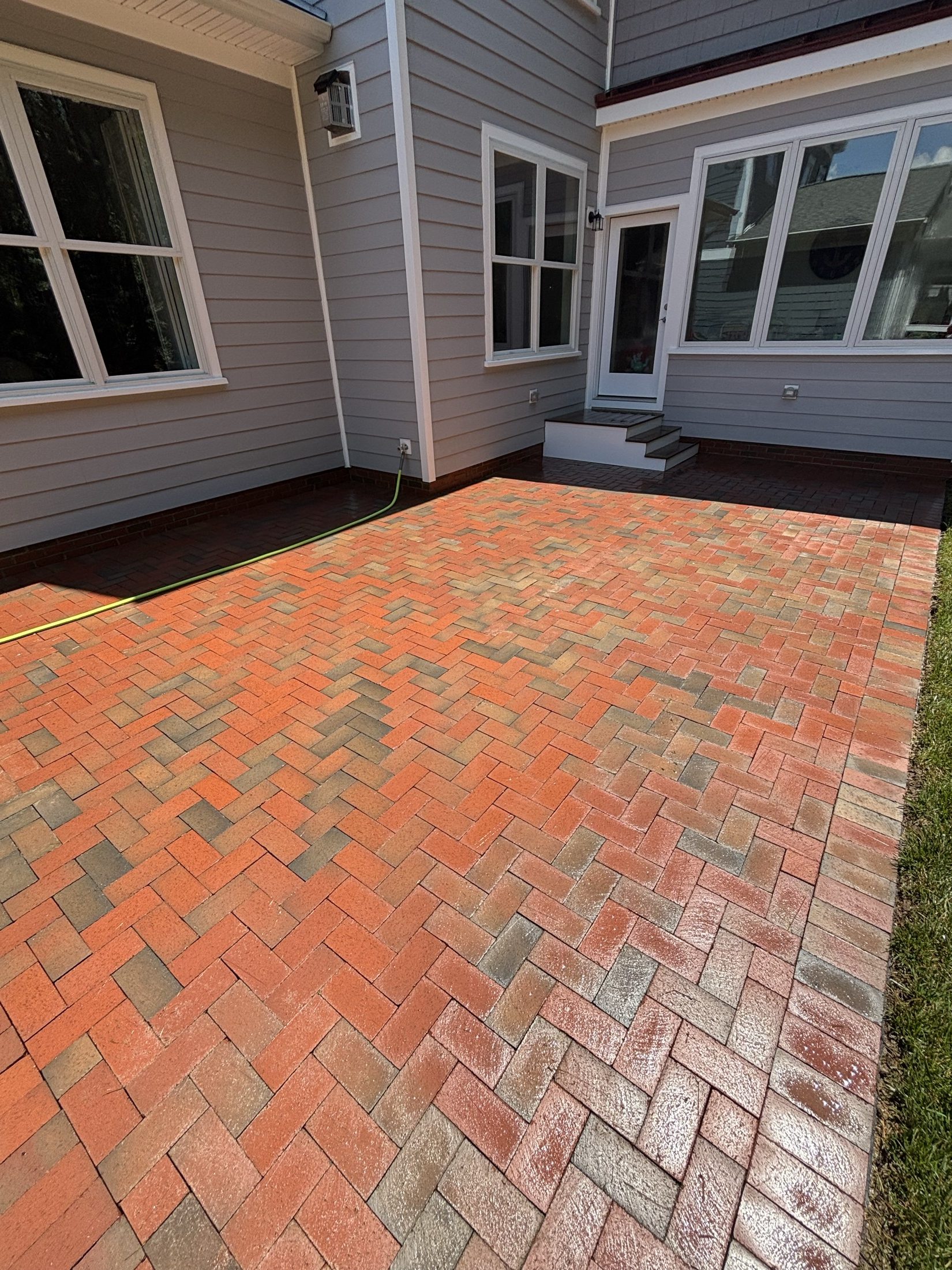 Freshly pressure-washed red brick paver walkway alongside a gray home in Easton MD on Maryland's Eastern Shore