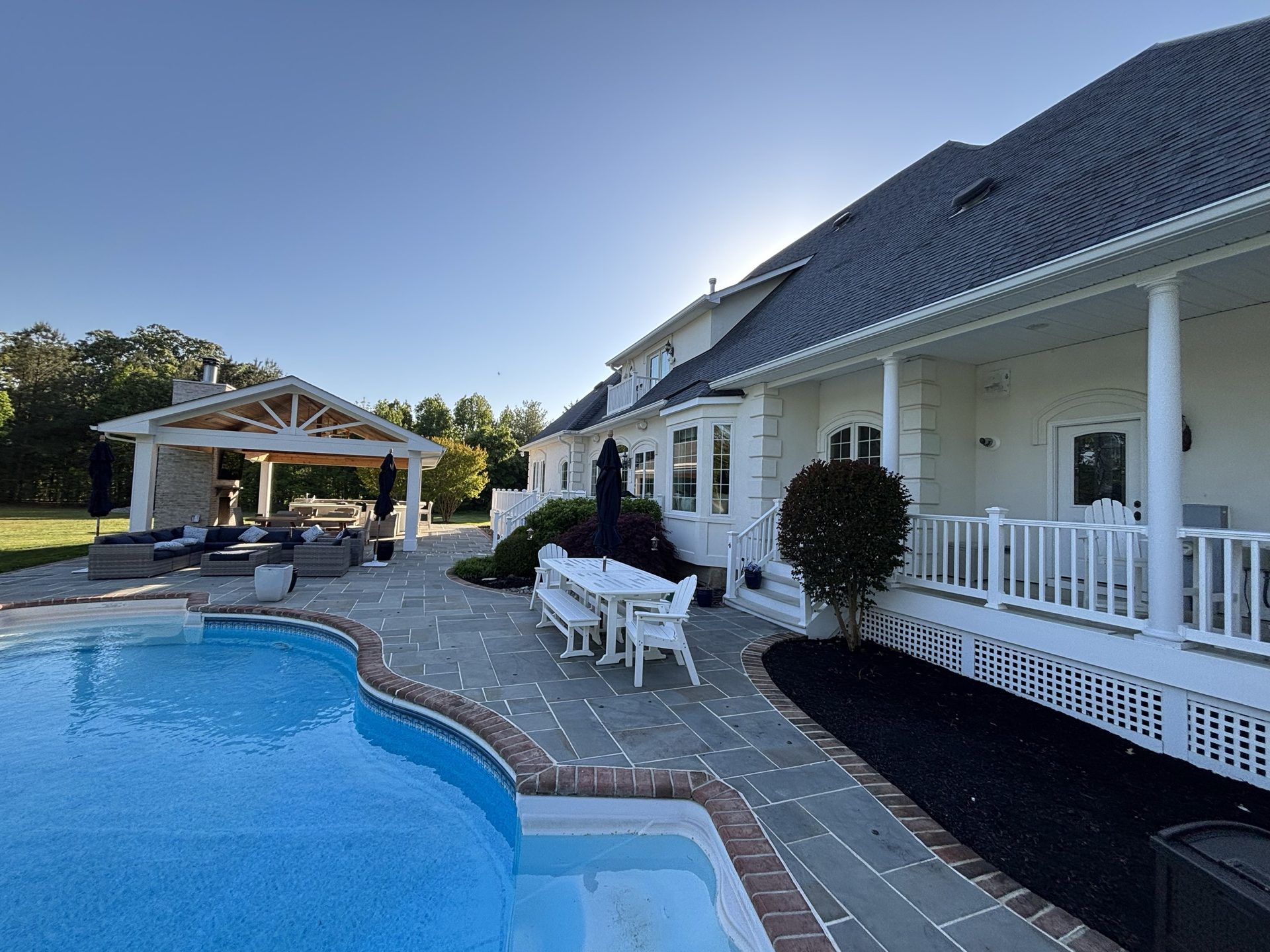 Pristine poolside patio and white home exterior after a professional pressure washing and soft washing treatment.
