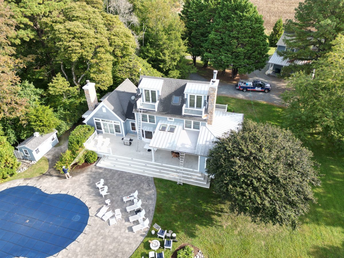 Aerial drone photo of a three-story blue coastal home with a pool and composite deck during a Coastal Shine house wash on Maryland's Eastern Shore